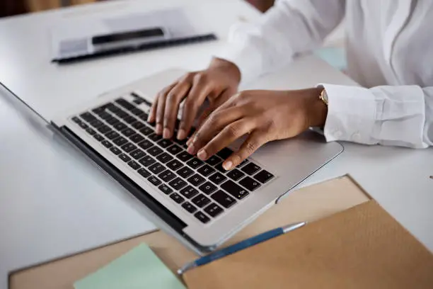 Photo of Shot of an unrecognisable businesswoman using a laptop in a modern office