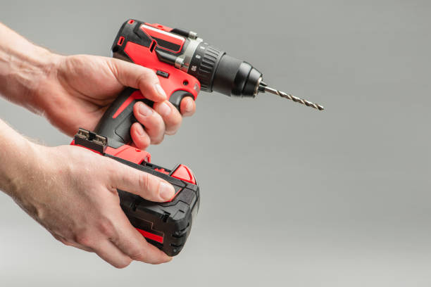 istock a man's hand removes the battery from a cordless tool. A man inserts a battery into a screwdriver. Repair and construction concept on gray background 1371717095