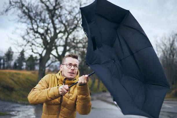 man with umbrella in wind and rain - kuvvetli yağmur stok fotoğraflar ve resimler