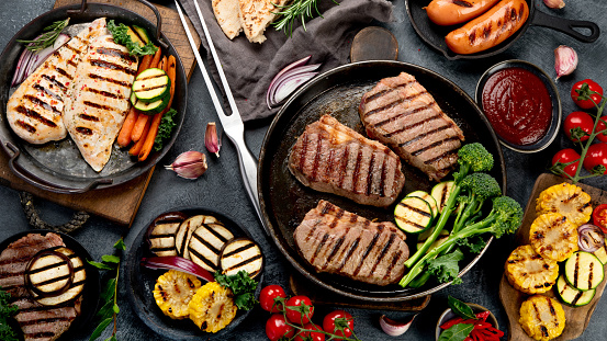 Grilled barbecue meat assortment on dark background. Homemade food concept. Top view, flat lay