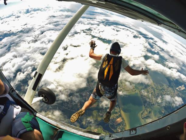 skydiver pula do avião sobre a praia - skydiving parachuting extreme sports airplane - fotografias e filmes do acervo