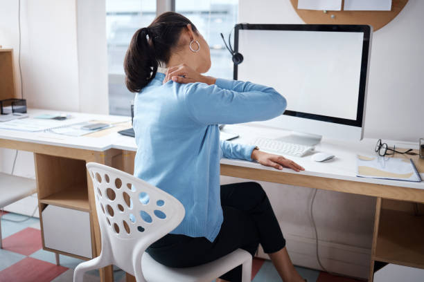 ujęcie bizneswoman doświadczającej bólu pleców podczas pracy przy biurku w nowoczesnym biurze - pain human neck working rear view zdjęcia i obrazy z banku zdjęć
