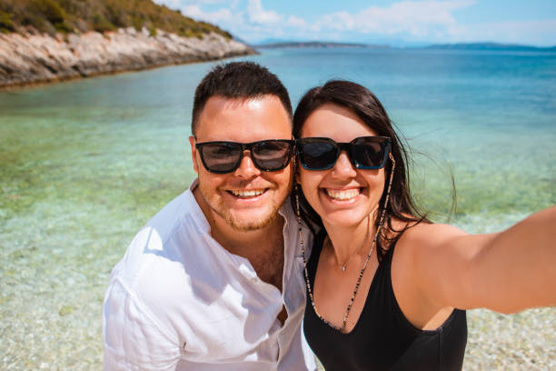 istock couple taking selfie at sunny day at sea beach 1371736621