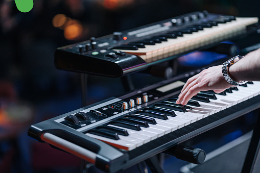 Close shooting of a keyboardist musician at work at a concert. Keyboardist play keyboard on stage.