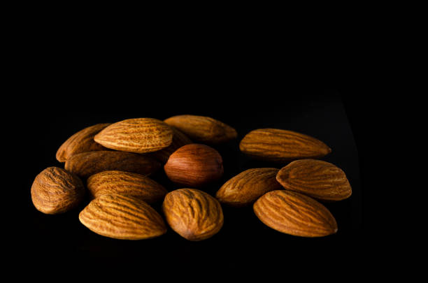 Appetizing almonds on a dark background. Mountain of almond mountains
