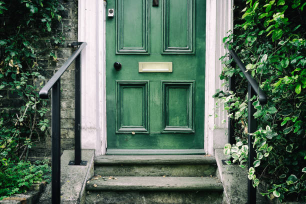 Traditional green-painted wooden door with traditional, victorian styled steps. Traditional green-painted wooden door with traditional, victorian styled steps leading to the front of a terraced victorian house in a mews area of London. key doormat stock pictures, royalty-free photos & images