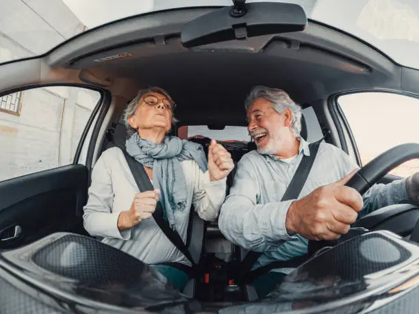 Photo of Couple of two happy senior dancing singing in vacations trip together driving and discovering new places with a car.