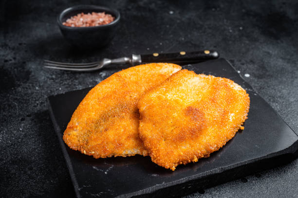 istock Fried breaded tilapia fillets on a marble board. Black background. Top view 1371748401