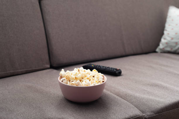 istock Bowl with popcorn and tv remote control on sofa 1371748416