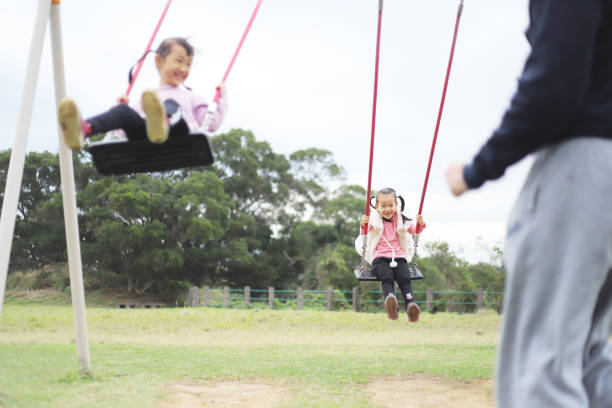 istock a father playing swings with his twin daughters. 1371748546