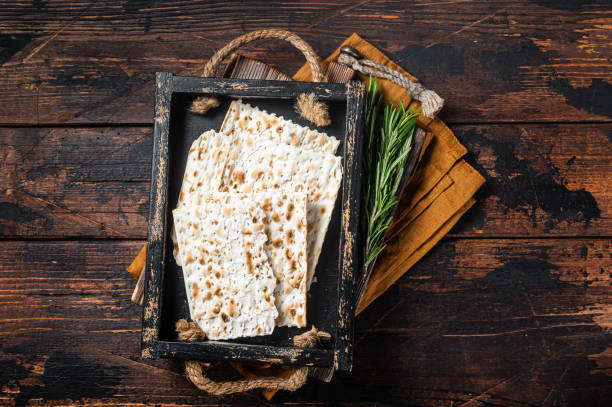 matzos di pasqua di celebrazione con pane azzimo matzo in un vassoio di legno con erbe. sfondo in legno. vista dall'alto - matzo passover cracker unleavened bread foto e immagini stock