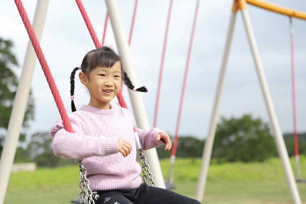 istock girls playing swing. 1371750499