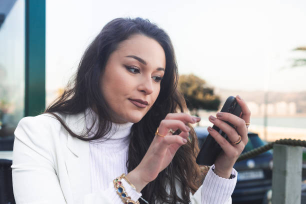 istock Young caucasian woman using a smartphone while taking a coffee and croisant at a terrace. 1371753810