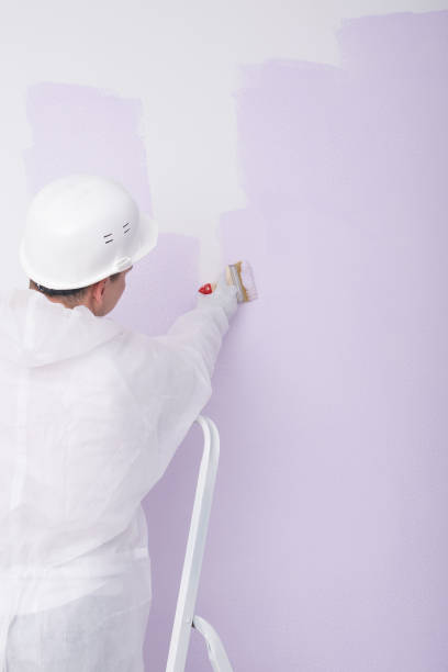 istock a man in a white helmet paints a white wall lilac 1371759848