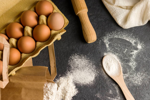 istock Traditional ingredients for baking. Natural fresh chicken eggs in eco package, flour, rolling pin on a dark kitchen table, linen towel. Top view. Flat lay. Kinfolk style. 1371765062