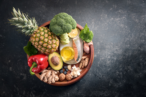 Collection of healthy food with anti-inflammatory and antioxidant on a wooden plate, immune system diet with fiber, vitamin, omega-3 and minerals, dark gray background, copy space, top view from above