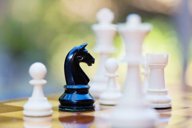 Lone black knight deep in white territory on a chessboard Black knight penetrates white's defence in a chess game. black knight stock pictures, royalty-free photos & images