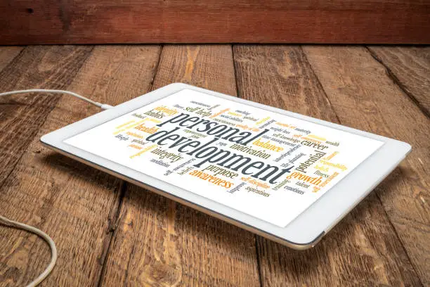 cloud of words or tags related to personal development on a digital tablet against rustic wood background