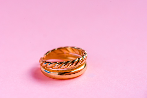 Women's jewelry in the form of gold ring with soft pink background
