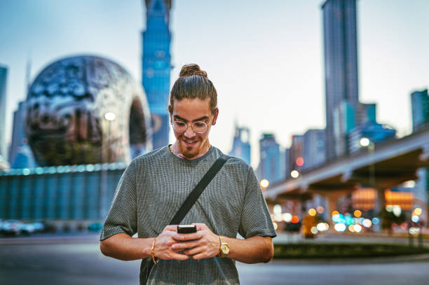 foto de un apuesto joven parado solo en la ciudad y usando su teléfono celular durante la noche - tourist map men holding fotografías e imágenes de stock