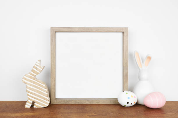 Mock up wood frame with Easter egg and bunny decor on a wood shelf Mock up wood frame with Easter egg and bunny decor on a wood shelf against a white wall. Copy space. white shabby chic desk stock pictures, royalty-free photos & images