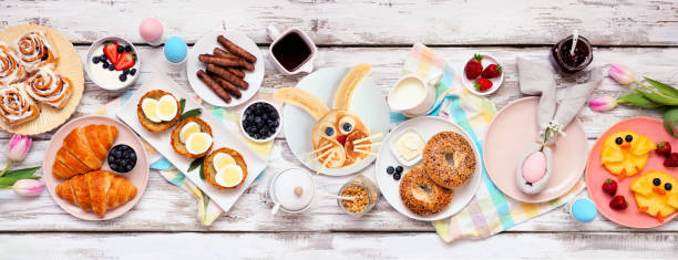 Easter breakfast or brunch table scene. Overhead view on a white wood banner background.