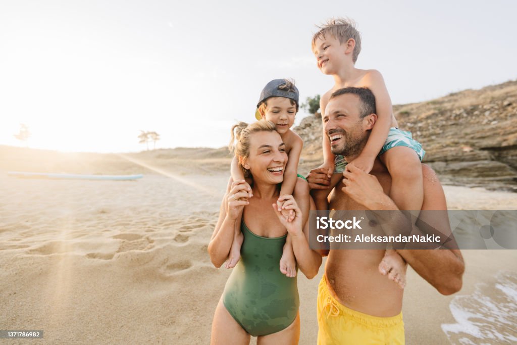 Four of us at the beach Photo of a smiling family at the beach Family Stock Photo