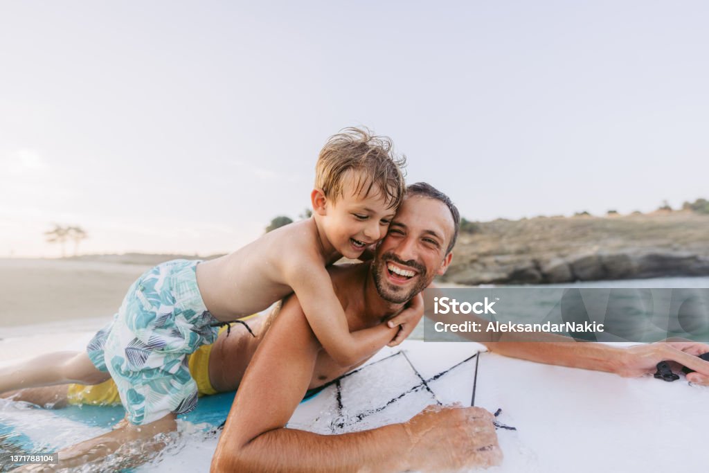 Partners for fun adventures Photo of father and son having fun while enjoying together on a paddleboard in the sea Greece Stock Photo