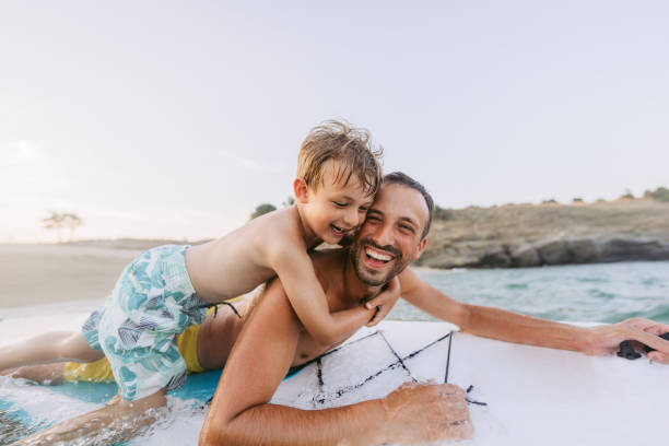 Partners for fun adventures Photo of father and son having fun while enjoying together on a paddleboard in the sea active lifestyle stock pictures, royalty-free photos & images
