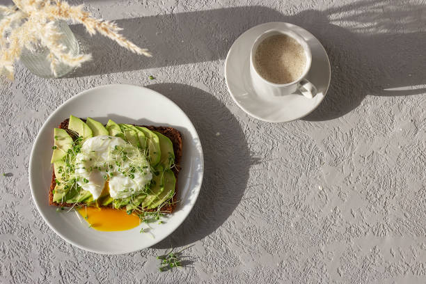 istock Healthy breakfast, toasted whole grain bread with avocado, poached egg, microgreens and a cup of coffee 1371788105
