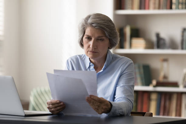 istock Focused middle aged businesswoman doing financial paperwork. 1371790507