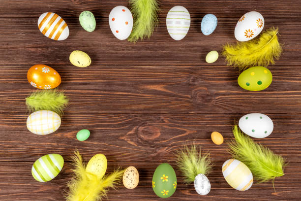Easter frame with eggs and feathers on a dark wooden background. Minimal concept. View from above. Place for text