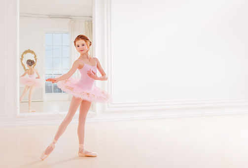 Little girl ballerina dancer in tutu dress learning ballet dance at dance school