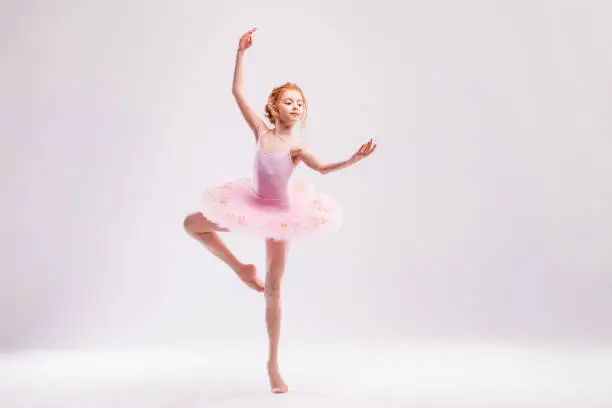 Little student ballerina dancer in pink tutu dress dreaming of becoming ballerina on white background