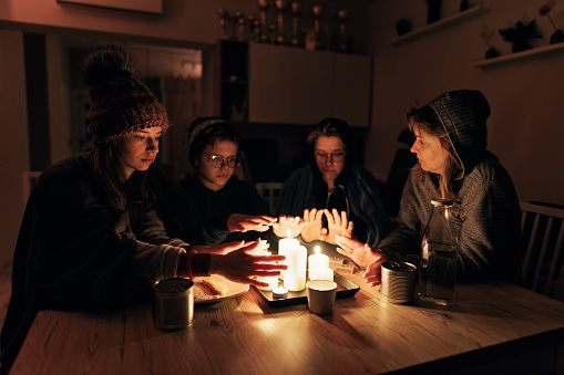 During the energy crisis family is sitting by the table, lit by candles. Everyone is wearing warm clothes because of heating problems during the power outage. They are eating dry biscuits and warming hands from the candle flame.
Canon R5
