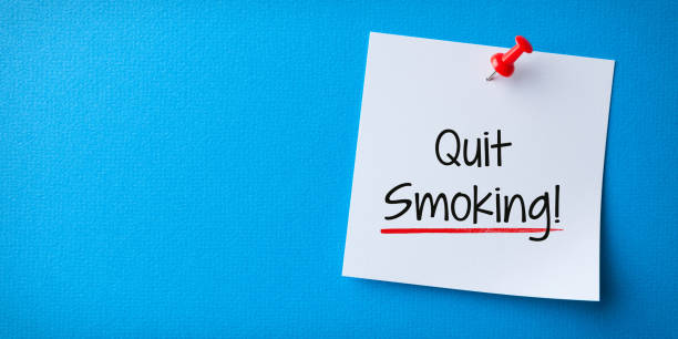 White Sticky Note With Quit Smoking And Red Push Pin On Blue Background stock photo