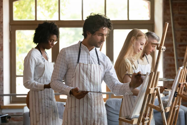 Smiling young multiracial people drawing on canvas.