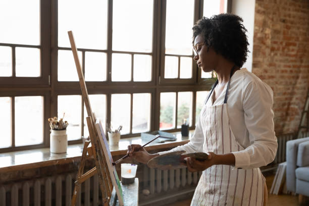Concentrated relaxed millennial African American drawing in studio.