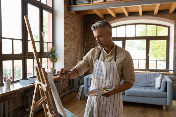 istock Focused skilled male artist creating artwork in studio. 1371797969