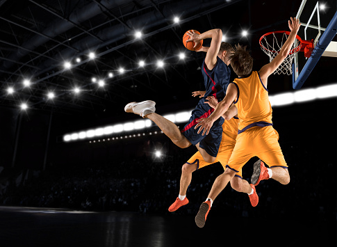 Three basketball player players in action on dark background