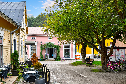 A small park with a sidewalk cafe and shops in the medieval village of Porvoo Finland.