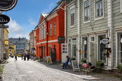 Tourists enjoy sightseeing and shopping on one of the cobblestone streets in the colorful, medieval town of Porvoo, Finland.