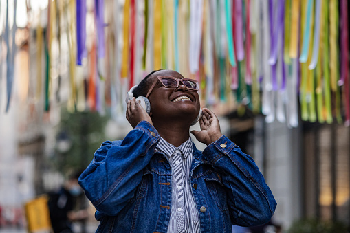 Mujer joven con auriculares inalámbricos escuchando música al aire libre photo