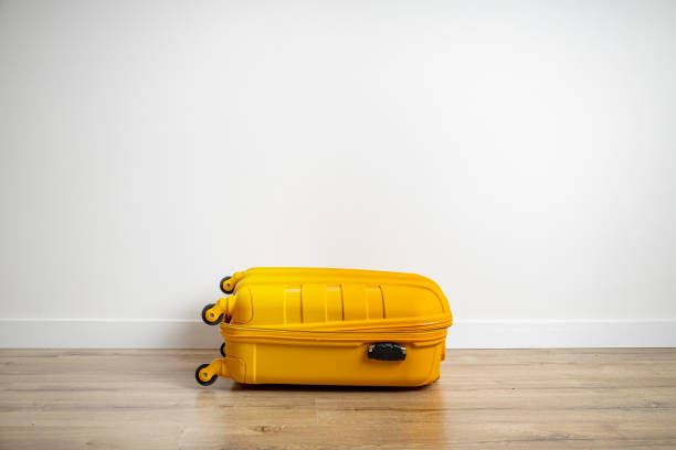 istock Yellow suitcase on a wooden floor against a white wall. 1371810579