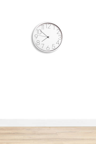 istock White large wall clock shows the time against a white wall. 1371811394