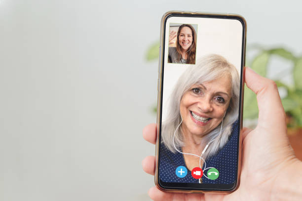 une personne âgée et sa fille heureuses parlent en appel vidéo avec un téléphone portable - focus sur le smartphone tenant la main - grandmother child grandparent isolated photos et images de collection