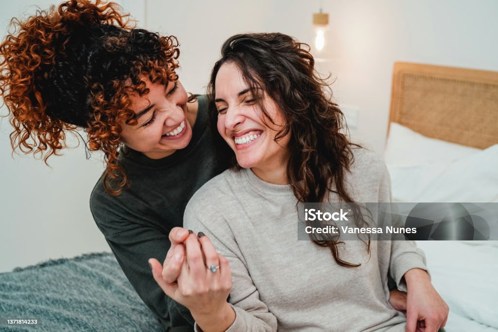 Happy gay women couple celebrating together with engagement ring in bed - Soft focus on right lesbian girl face Couple - Relationship Stock Photo