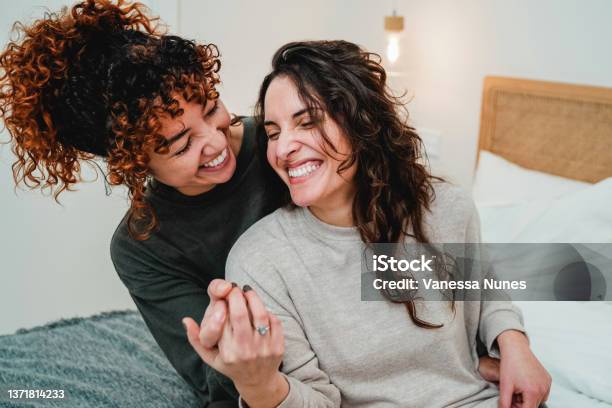 Happy Gay Women Couple Celebrating Together With Engagement Ring In Bed Soft Focus On Right Lesbian Girl Face Stock Photo - Download Image Now