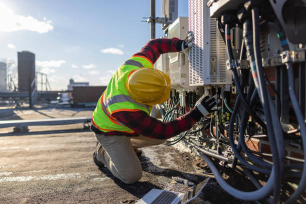 istock A blue-collar worker, a repairman, is checking and servicing telecommunication equipment mounted on a rooftop. 1371815086