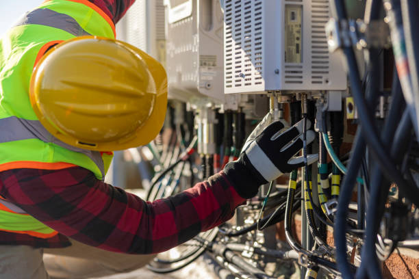 A blue-collar worker, a repairman, is checking and servicing telecommunication equipment mounted on a rooftop. A blue-collar worker, a repairman, is checking and servicing telecommunication equipment mounted on a rooftop. helmet hardhat protective glove safety stock pictures, royalty-free photos & images